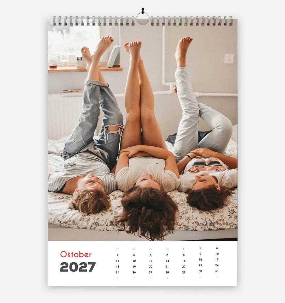 enostavna_base2 Three friends lying on bed with legs up, October 2027 calendar visible.