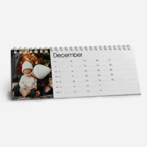 December desk calendar with a festive photo of children reading near Christmas decorations.