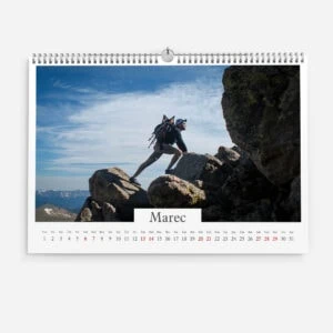 Hiker climbing rocky mountain terrain with backpack and helmet in daylight.