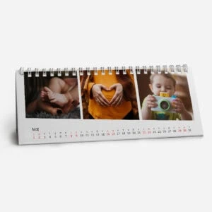 Photograph of a desk calendar with three images of children and a heart shape.