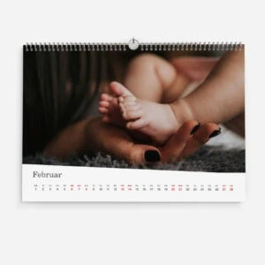 Close-up of a baby's feet held in an adult's hand, February calendar background.