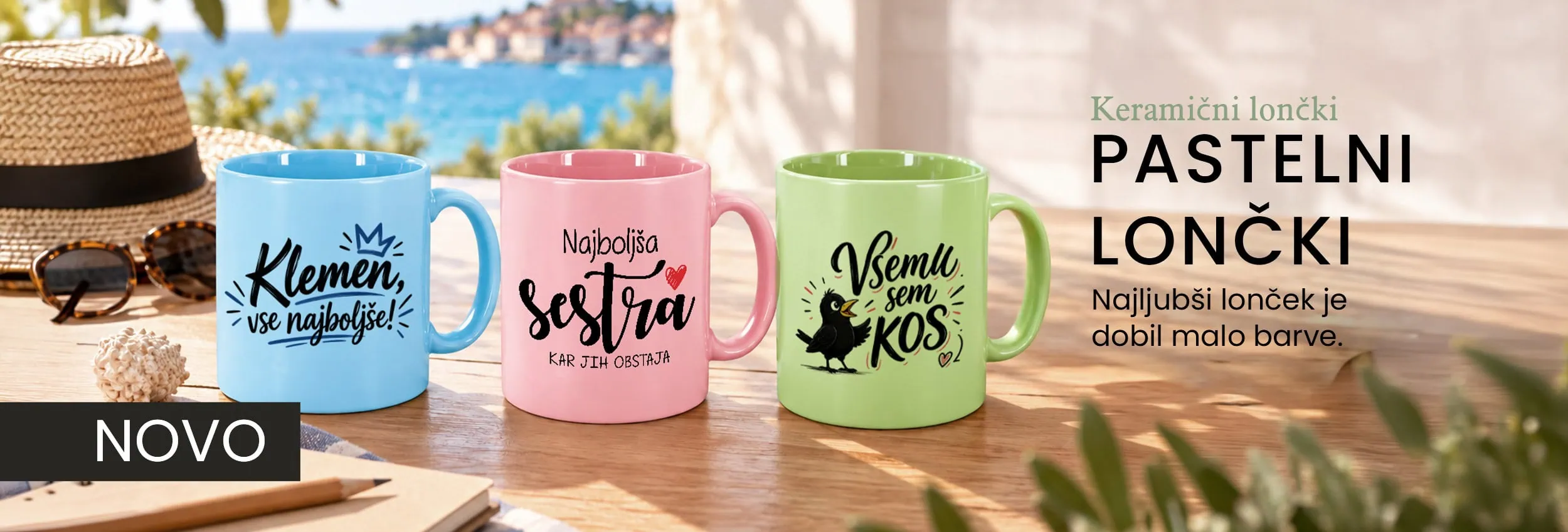 Colorful ceramic mugs with personalized messages on a wooden table near the sea.
