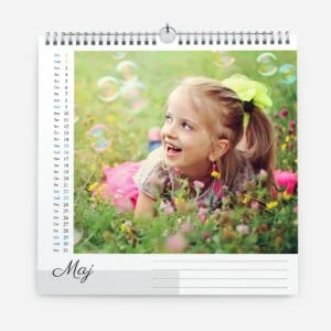 Child lying in a flower garden with bubbles and a bright green bow in her hair.