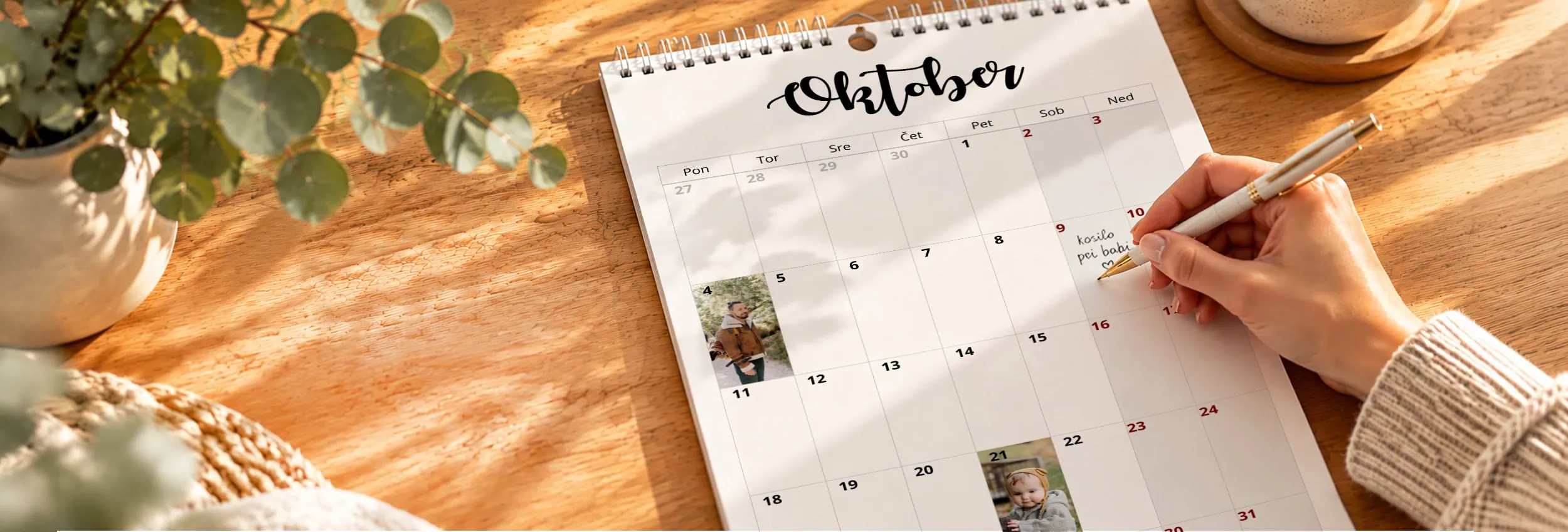 Person writing on October calendar with a pen on a wooden desk.